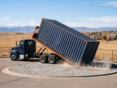 Tilt-bed truck unloading a container